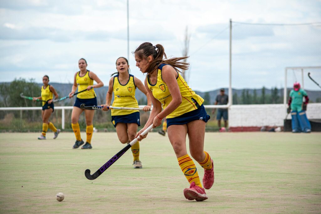 Energetic field hockey game with focused female players on an outdoor field.