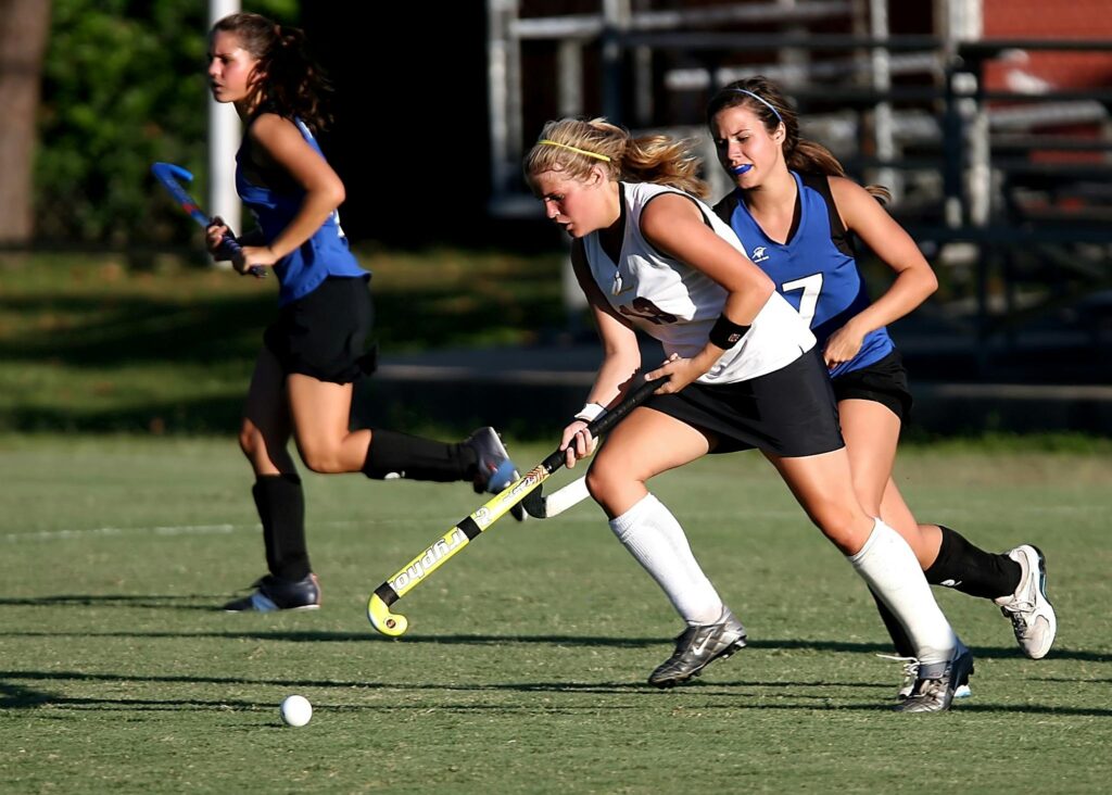 Energetic field hockey game with women players competing outdoors.